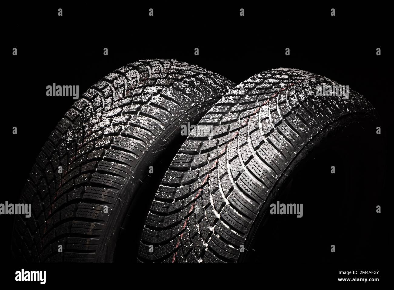 Winter Car tire with snow on black background. Tyre and snowflakes with copy space for text. Stock Photo