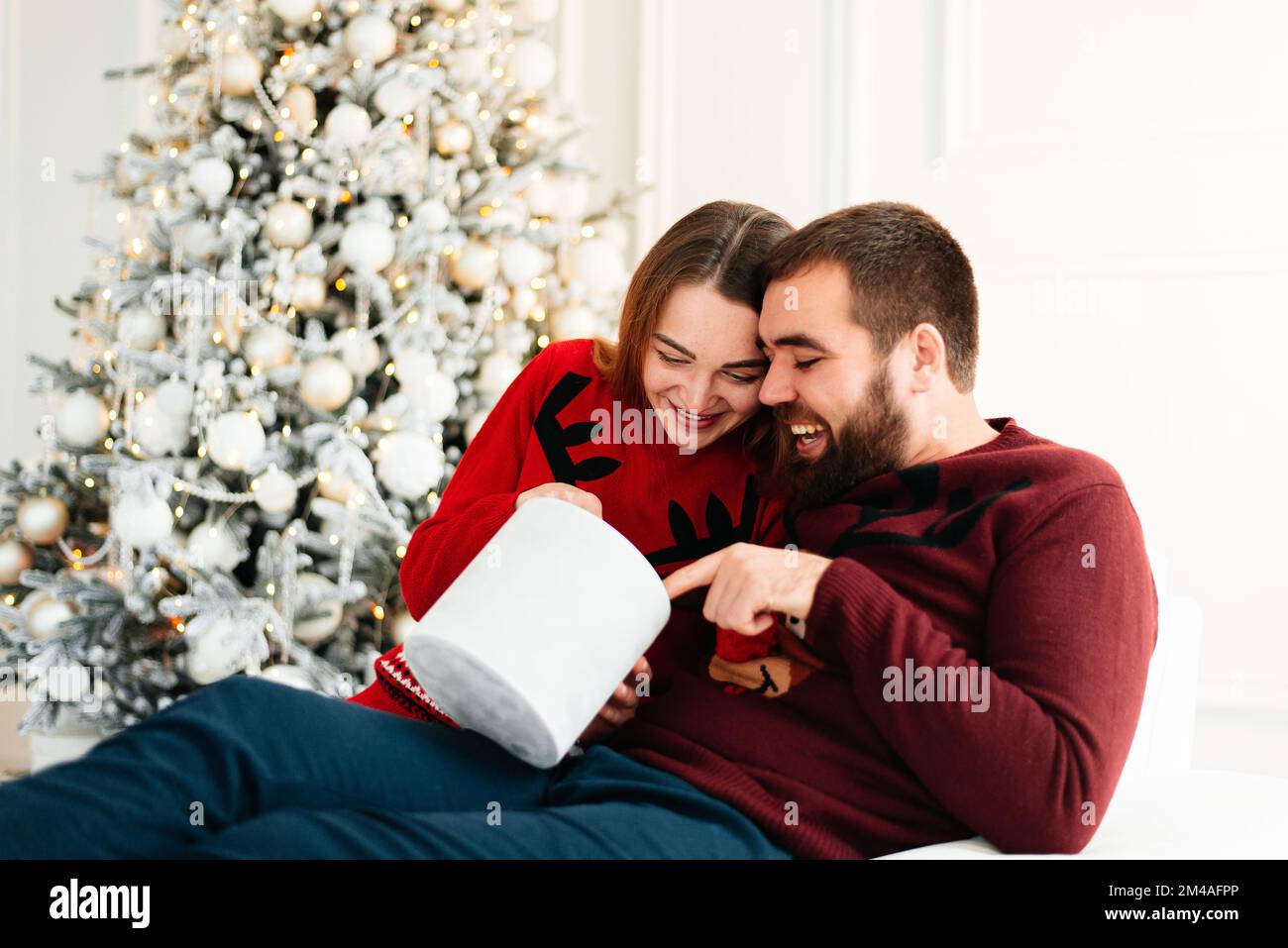 Cheerful man and woman opening a Christmas present Stock Photo