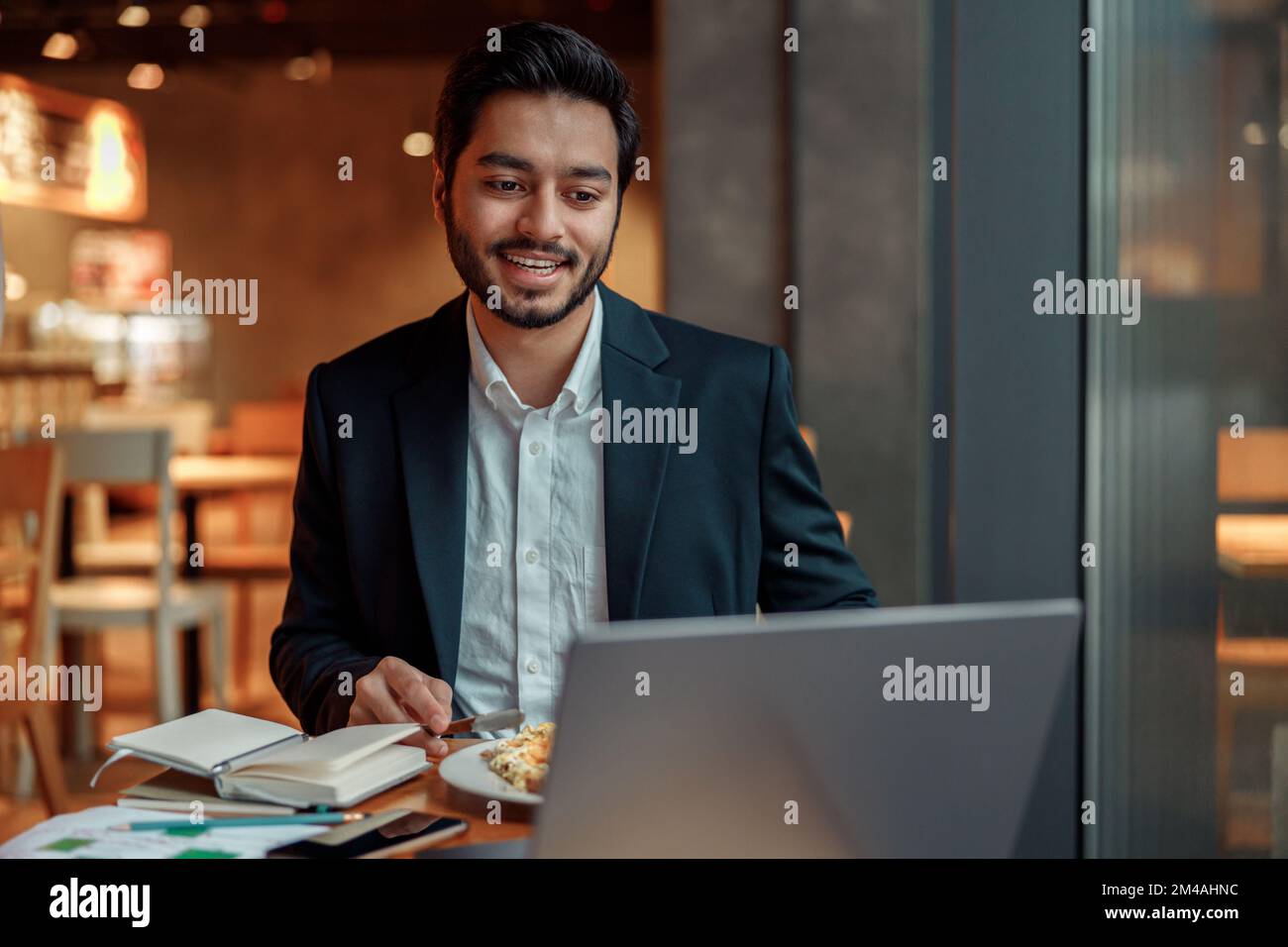 Handsome indian businessman working on laptop in cozy cafe sitting near window Stock Photo