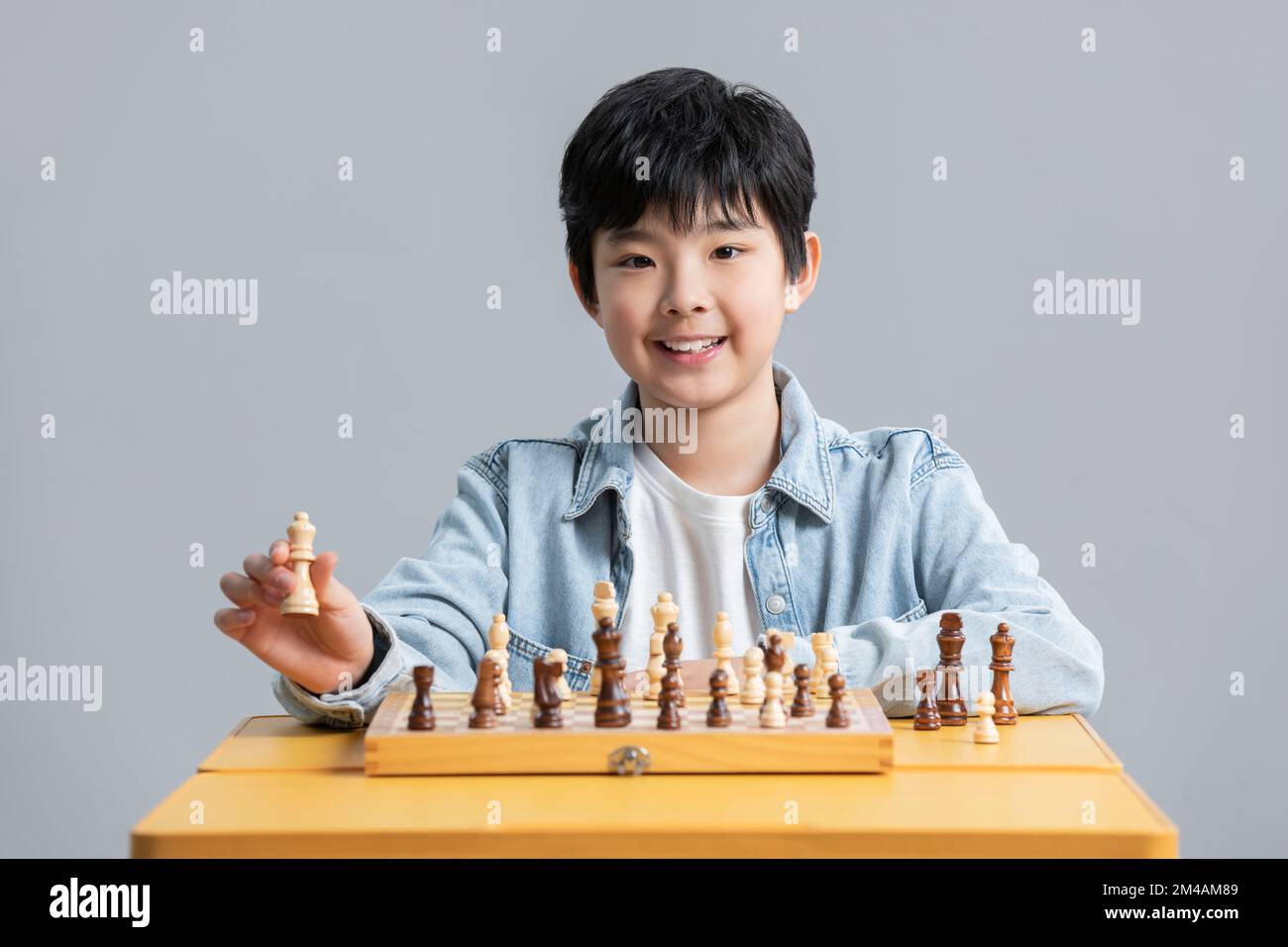 Cheerful Chinese boy playing chess Stock Photo