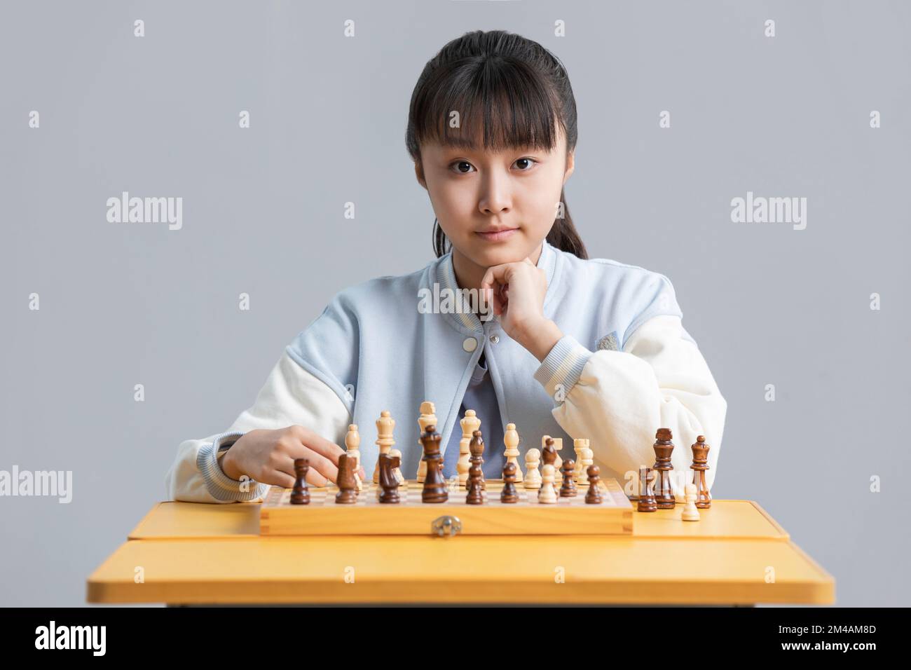 Cheerful Chinese girl playing chess Stock Photo