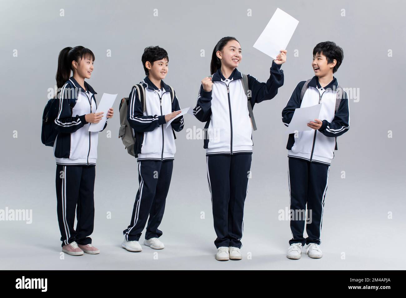 Cheerful Chinese students in uniform celebrating for their test results Stock Photo