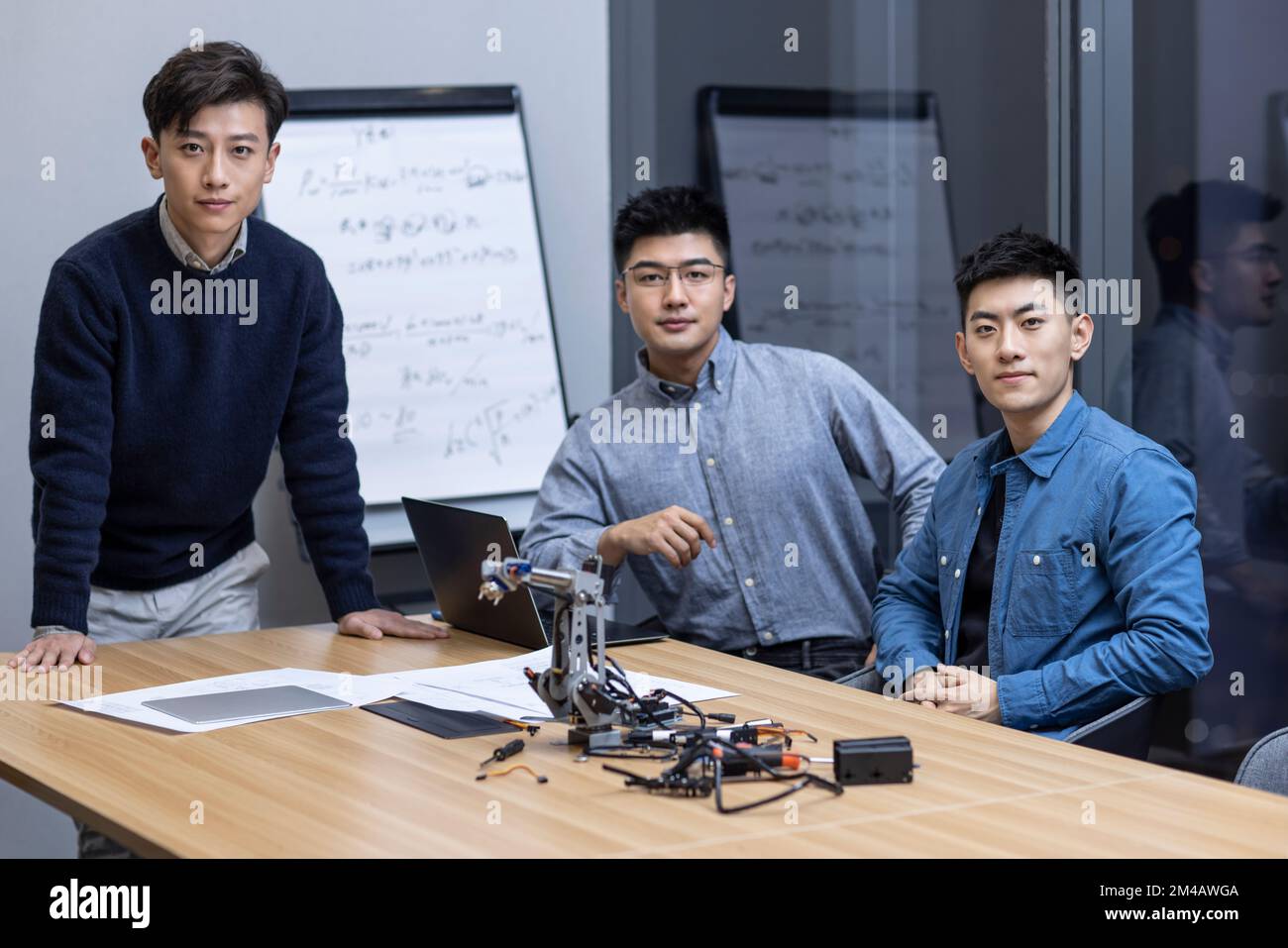 Confident Chinese designers checking a robotic arm Stock Photo