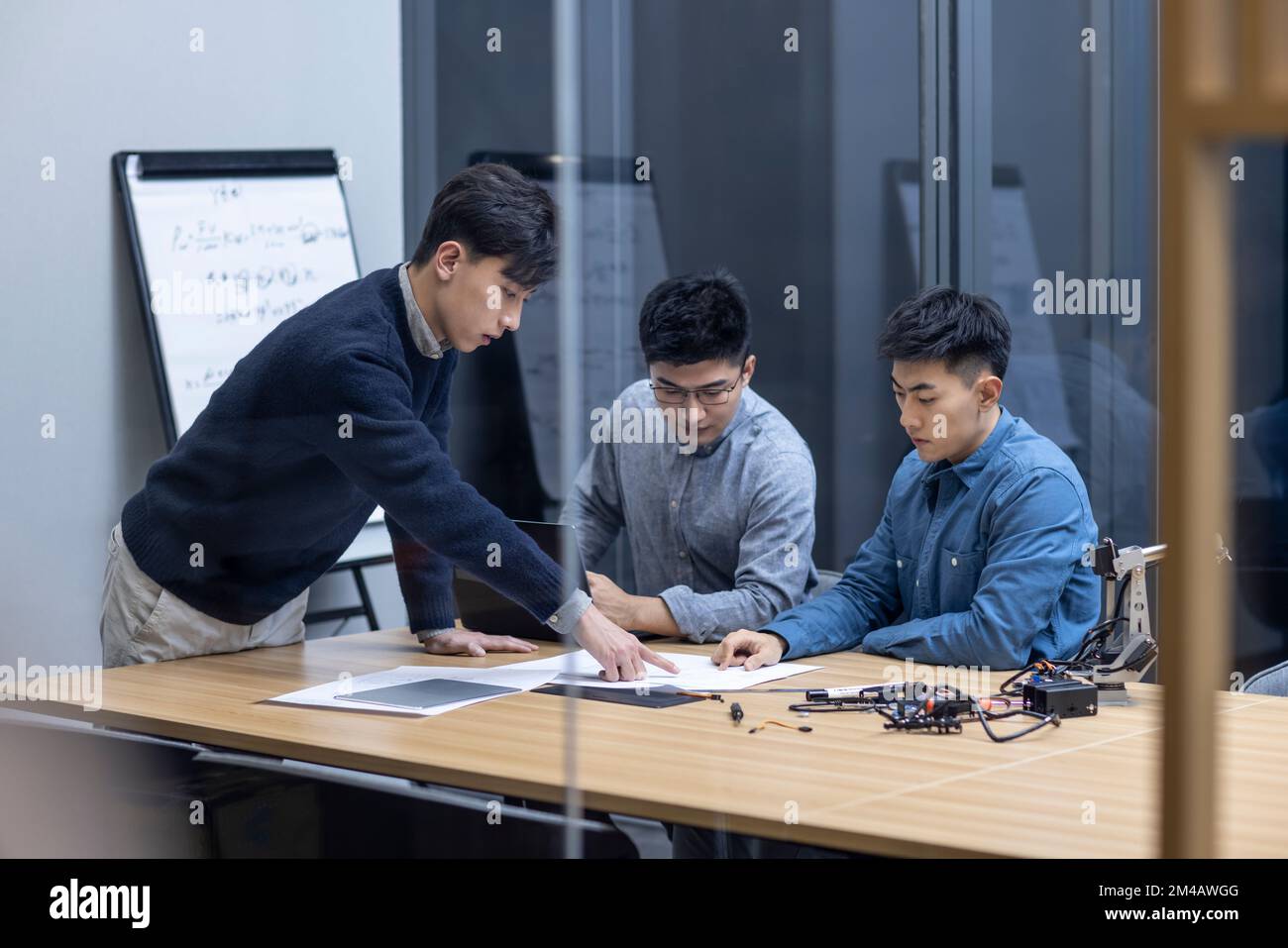 Confident Chinese designers checking a robotic arm Stock Photo