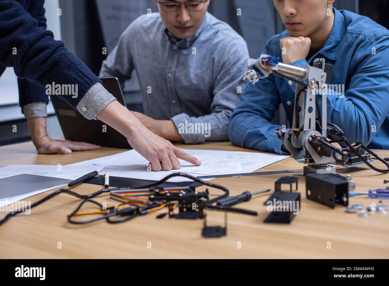 Confident Chinese designers checking a robotic arm Stock Photo