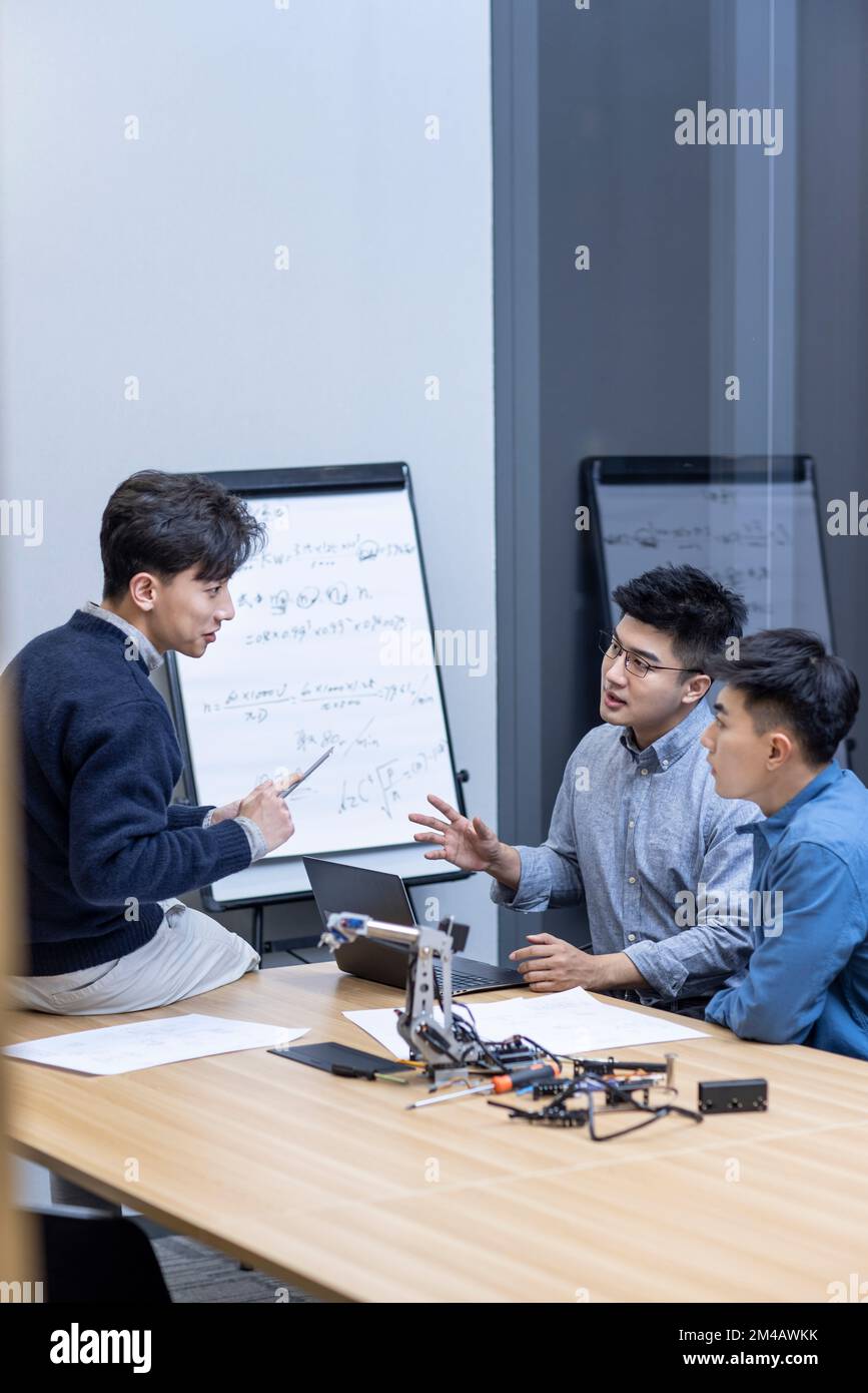Confident Chinese designers checking a robotic arm Stock Photo