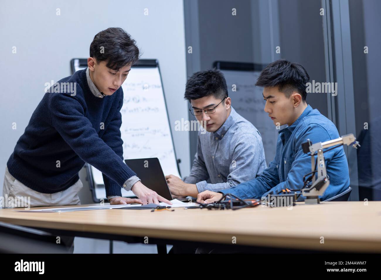 Confident Chinese designers checking a robotic arm Stock Photo