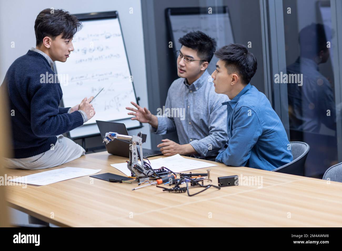 Confident Chinese designers checking a robotic arm Stock Photo