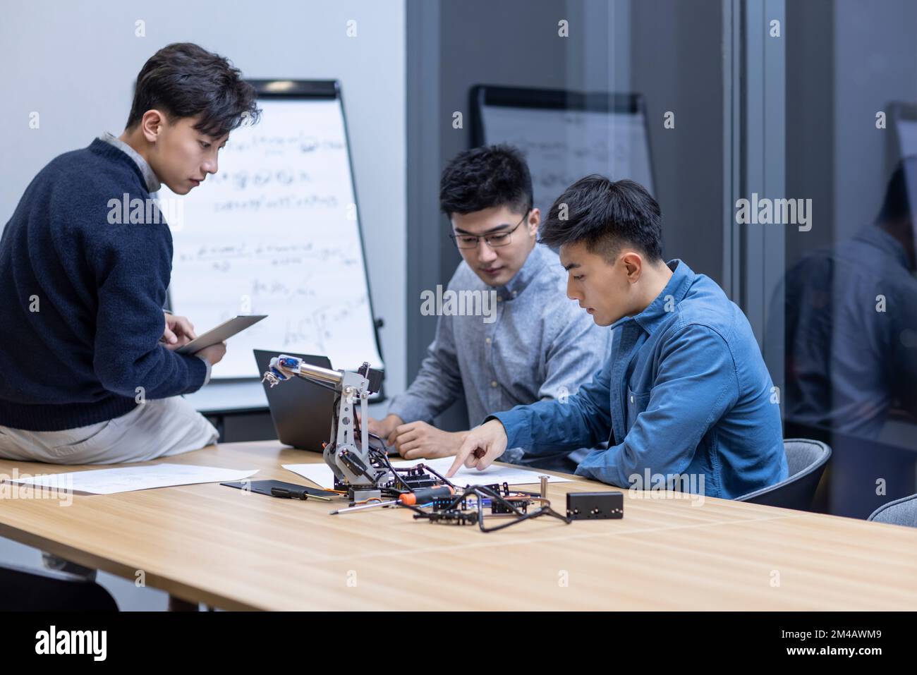 Confident Chinese designers checking a robotic arm Stock Photo