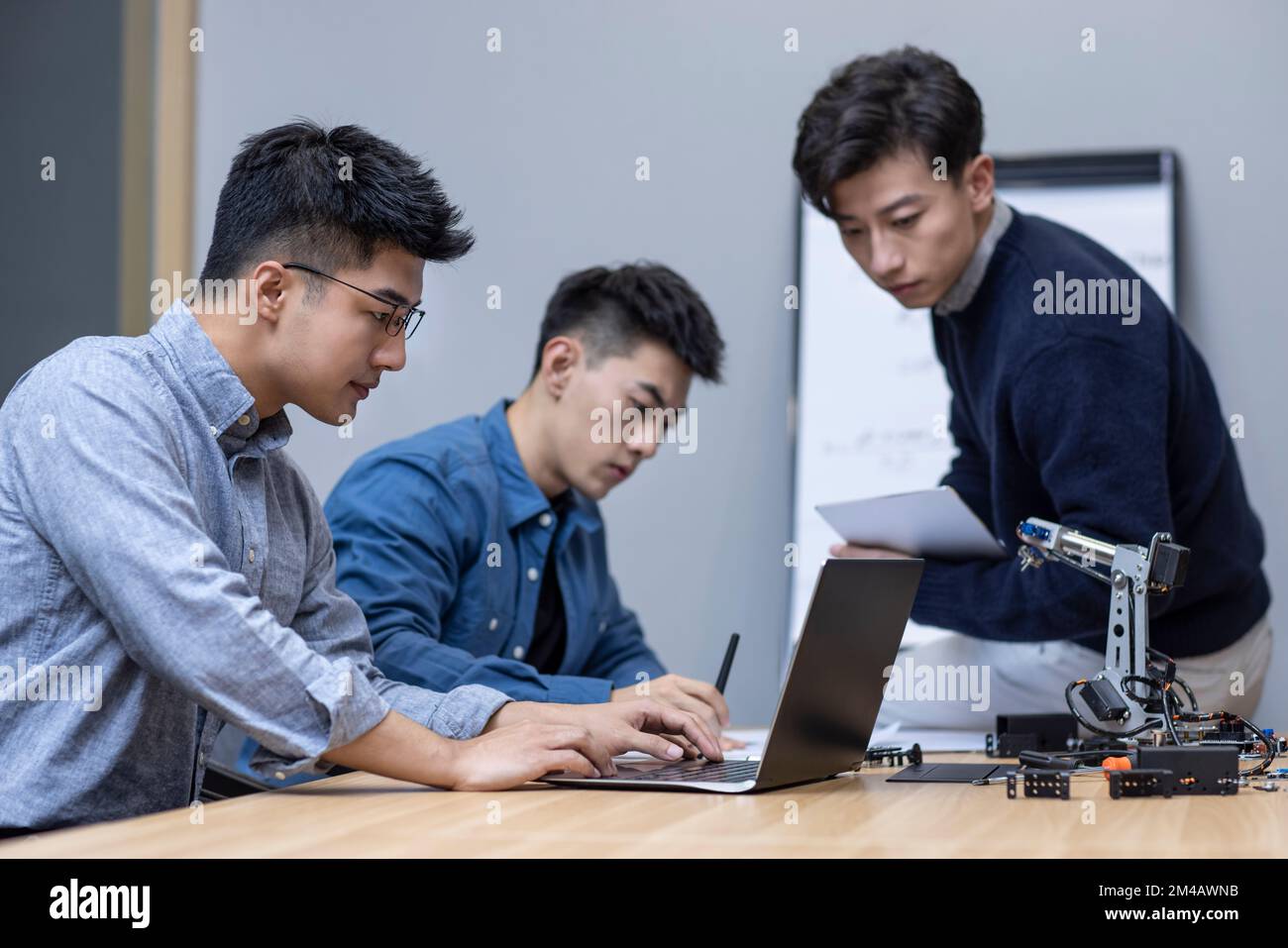 Confident Chinese designers checking a robotic arm Stock Photo