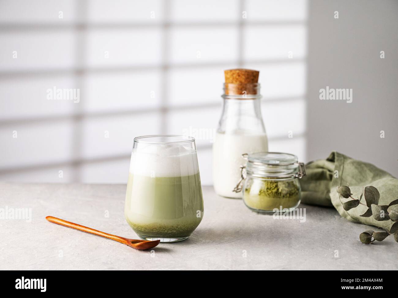 Green matcha latte in a glass on a gray background with morning shadows ...