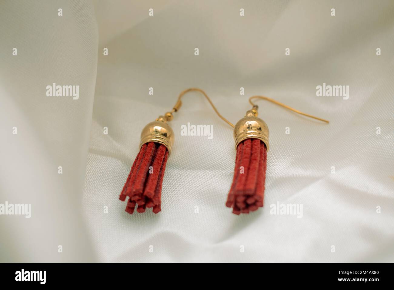 A closeup shot of red and gold earrings on a white background Stock Photo