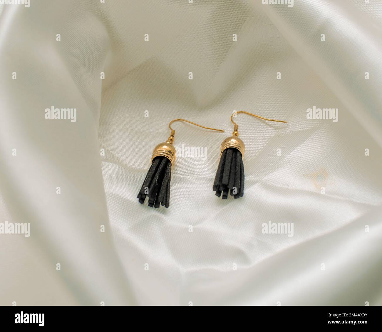 A closeup shot of black and gold earrings on a white background Stock Photo