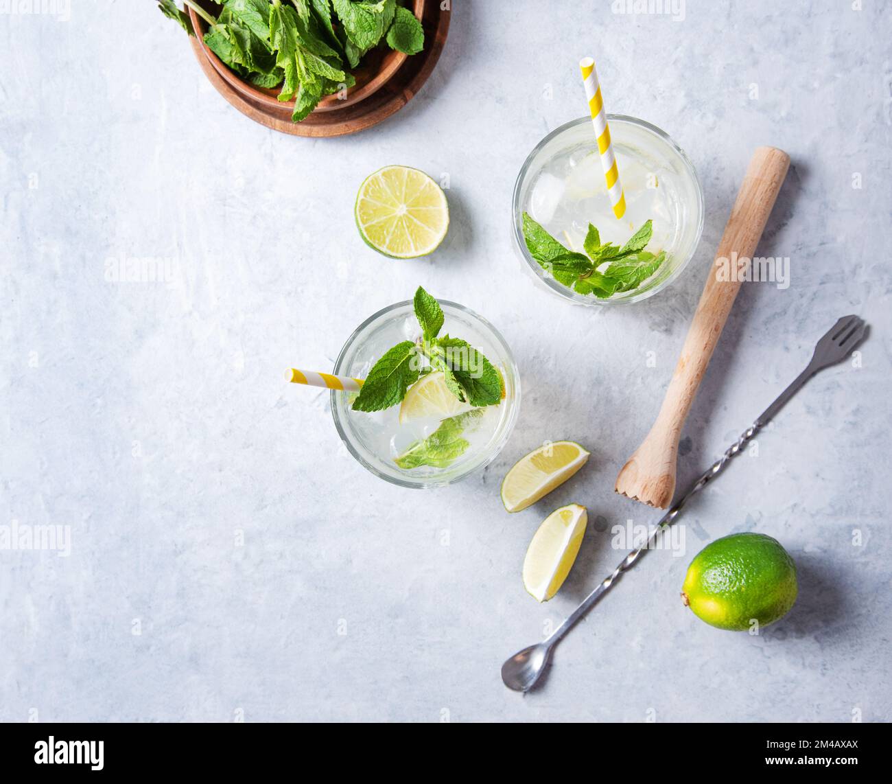 Concept flatlay mojito drink. Two glasses of lime lemonade with lime slices,  juicer, spoon and mint on white background . top view and copy space  im Stock Photo