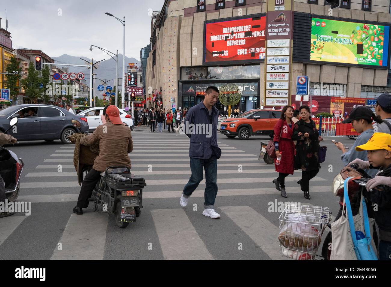 Pedestrians and vehicles at an intersection in the modern part of Lhasa city.  Tibet Autonomous Region. China. Stock Photo