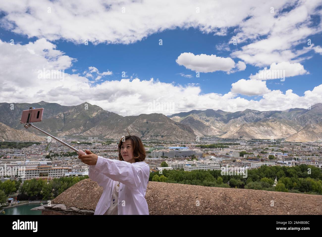 Chinese tourist takes a selfie with the city of Lhasa in the background.  Tibet Autonomous Region. China. Stock Photo
