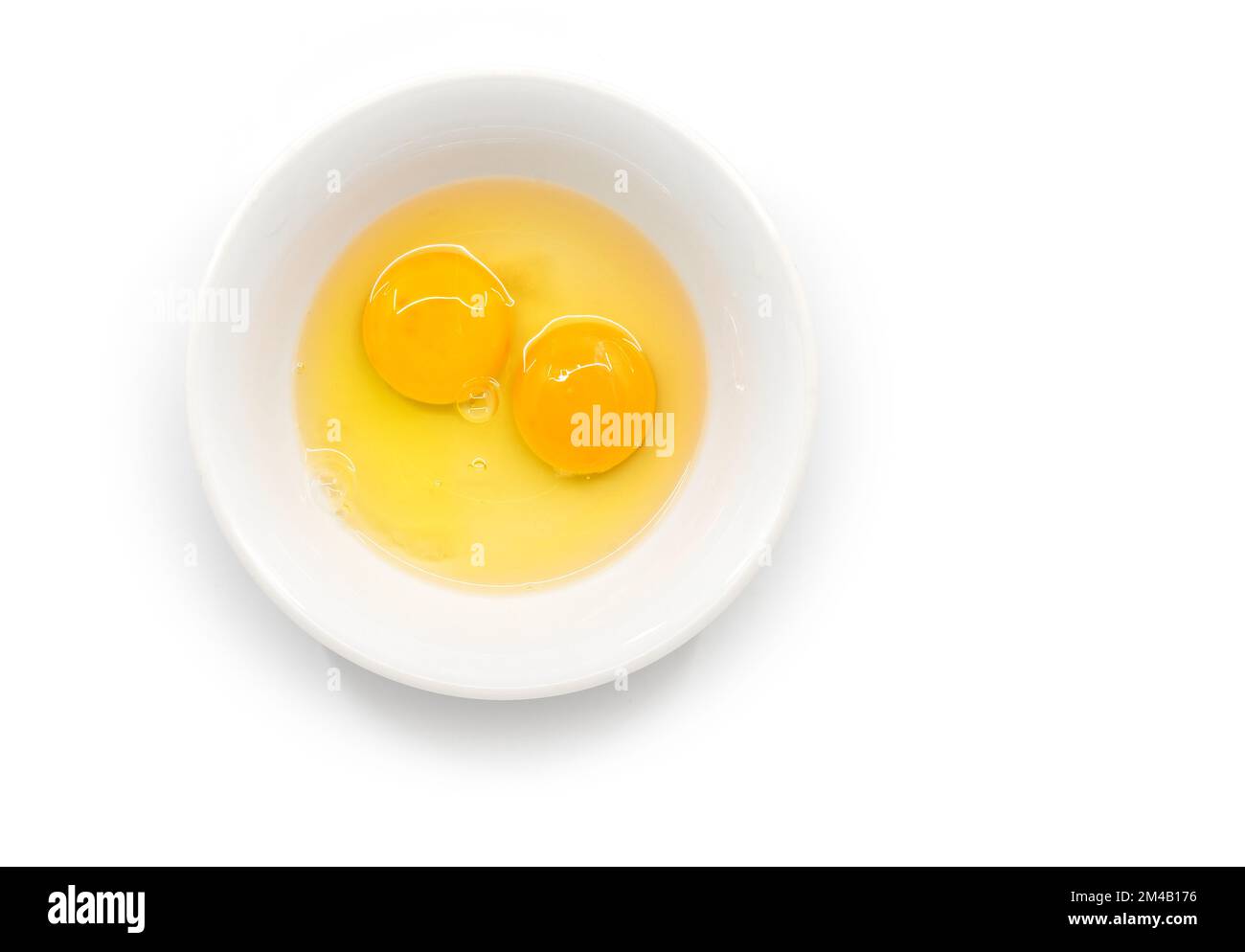 Isolated raw chicken eggs, top view of two raw egg yolk in white bowl on white background. Stock Photo