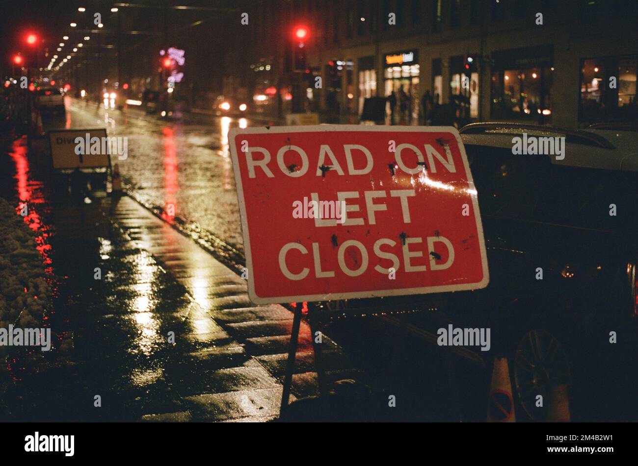 'Road on left closed' and 'Diversion' construction signs at night, Edinburgh, Scotland Stock Photo