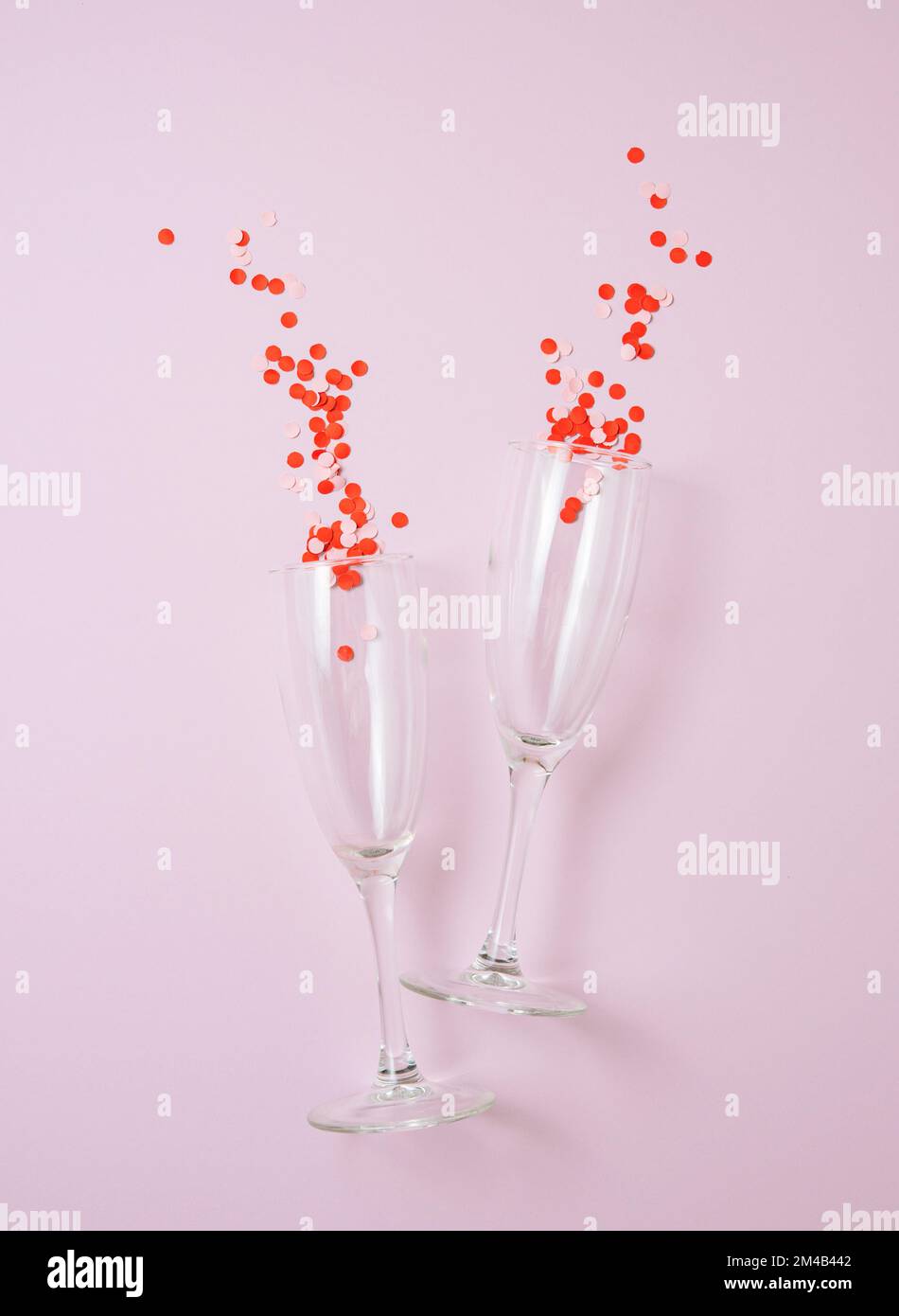 Flat lay of celebration. Two glasses with confetti  on a pastel pink  background. Concept of Valentine's Day, Mother's Day, wedding day. Top view Stock Photo