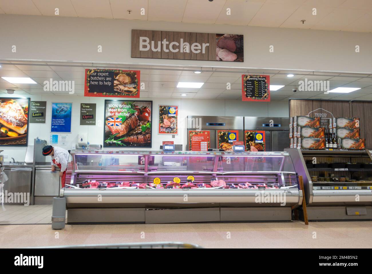Butcher at Tesco with employee wiping down counter, ashford, kent, uk