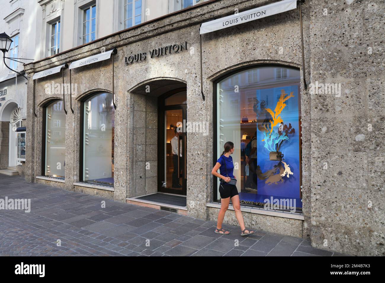 SALZBURG, AUSTRIA - AUGUST 4, 2022: People visit luxury handbag fashion store Louis Vuitton in Salzburg, Austria. High end French brand Louis Vuitton Stock Photo