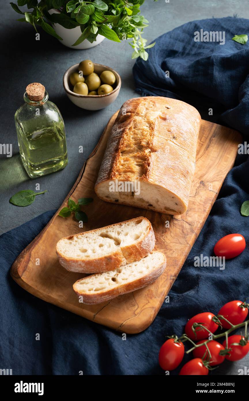 Italian ciabatta bread cut  slices with tomato, basil and olive on dark background.  Top view. Stock Photo