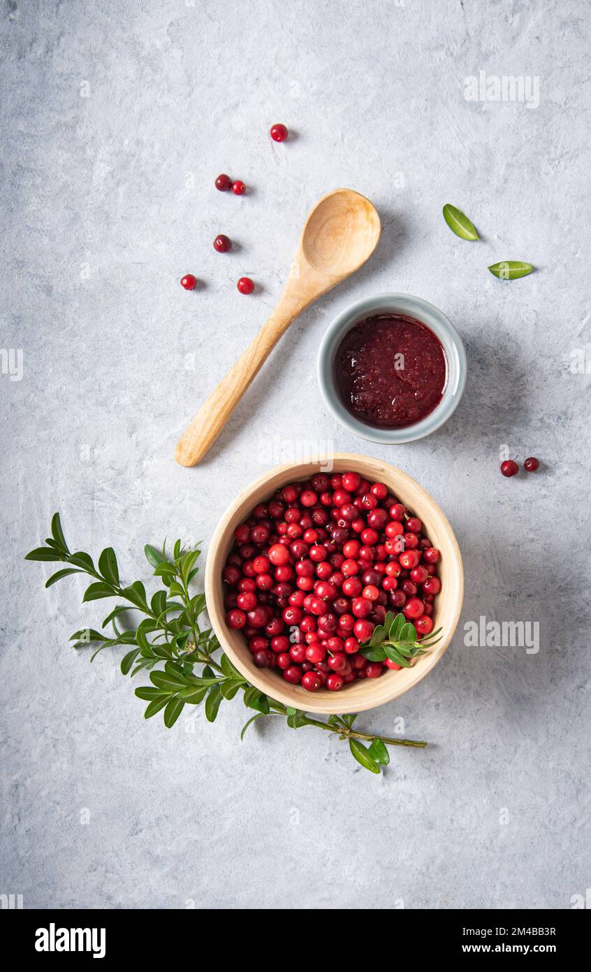 juicy forest lingonberry with handmade jam  in a wooden bowl on white table. Concept homemade healthy food. Top view and copy space image Stock Photo