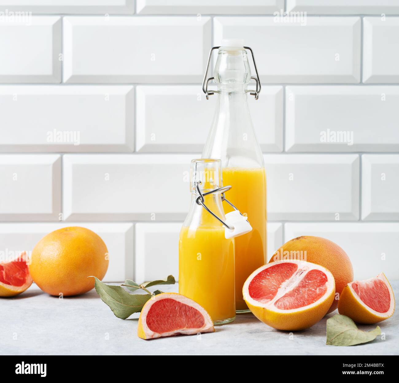 juicy and fresh grapefruit and bottle juice on a blue table on  a white brick background. Concept healthy and diet  food. Front view and copy space. Stock Photo