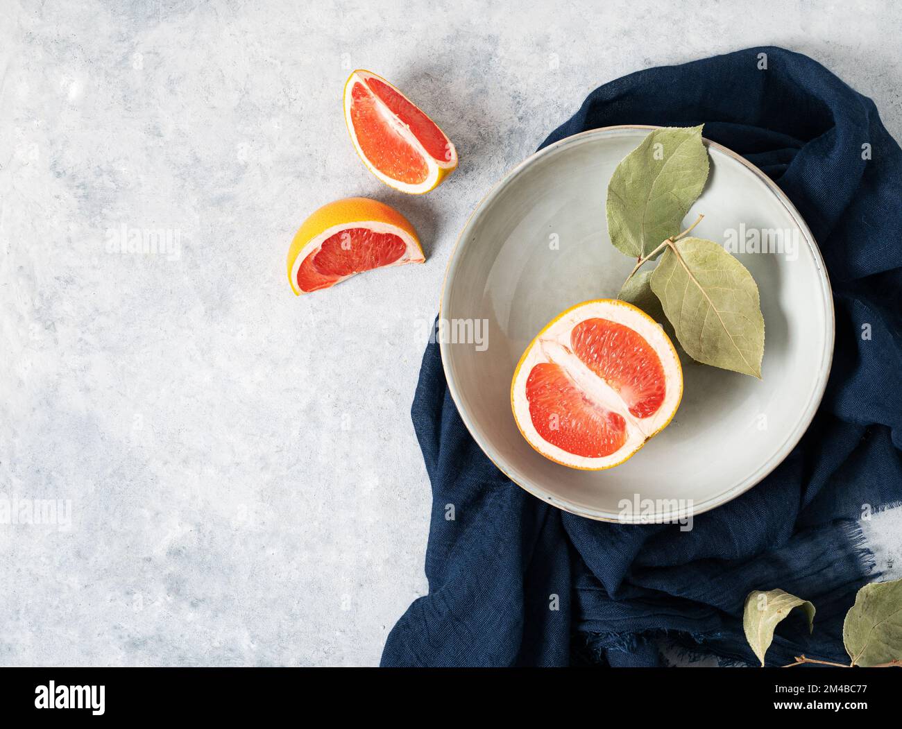 juicy red grapefruit in a plate and slices on a blue background with a dark napkin. Concept healthy food. Top view and copy space. Stock Photo