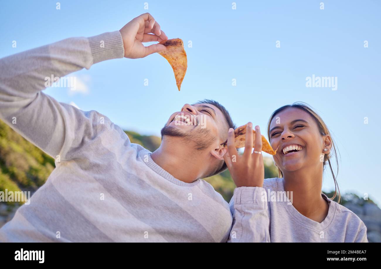 Pizza, comic and couple of friends in nature, lunch freedom and happy on a date in Portugal. Food love, funny and man and woman with fast food eating Stock Photo