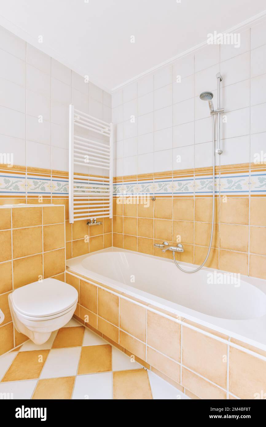 a bathroom with orange and white tiles on the walls, tub, toilet, and