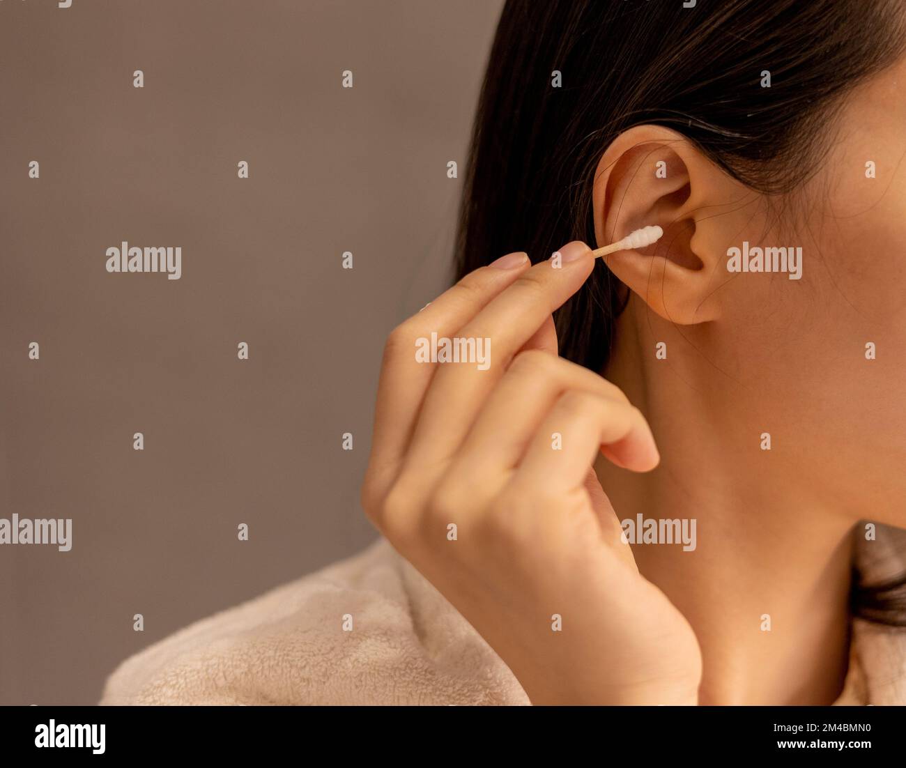 Woman cleaning her ear with a cotton swab after taking a shower