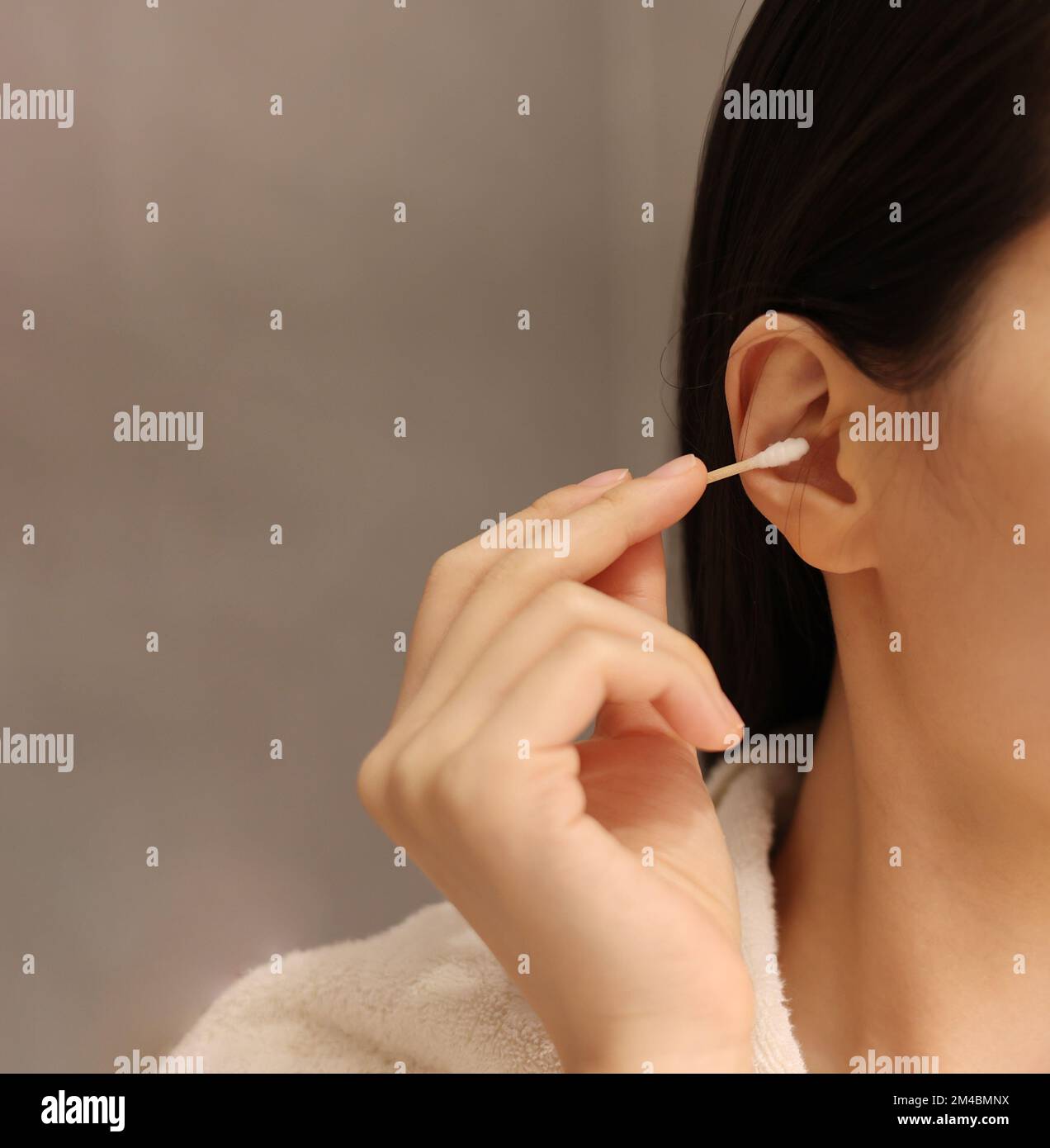 Woman cleaning her ear with a cotton swab after taking a shower