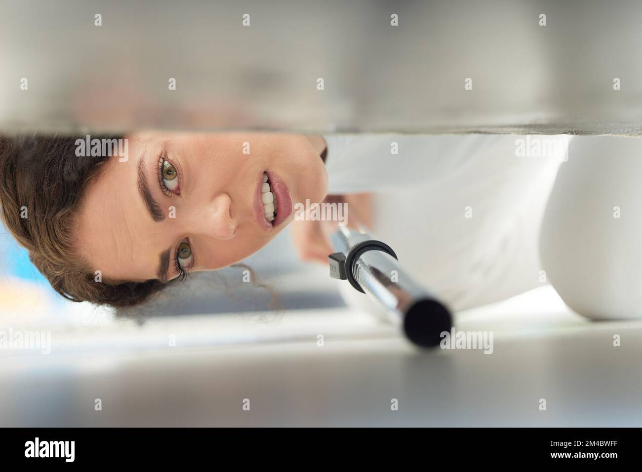 Cleaning, vacuum and face of woman under sofa for housework or hygiene