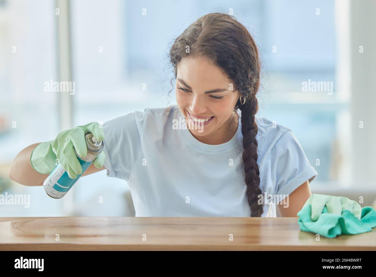 Cleaning, table and happy woman spray with cloth for dirt, dust or bacteria on furniture at home. Happy cleaner, housekeeping and maid wipe wood Stock Photo