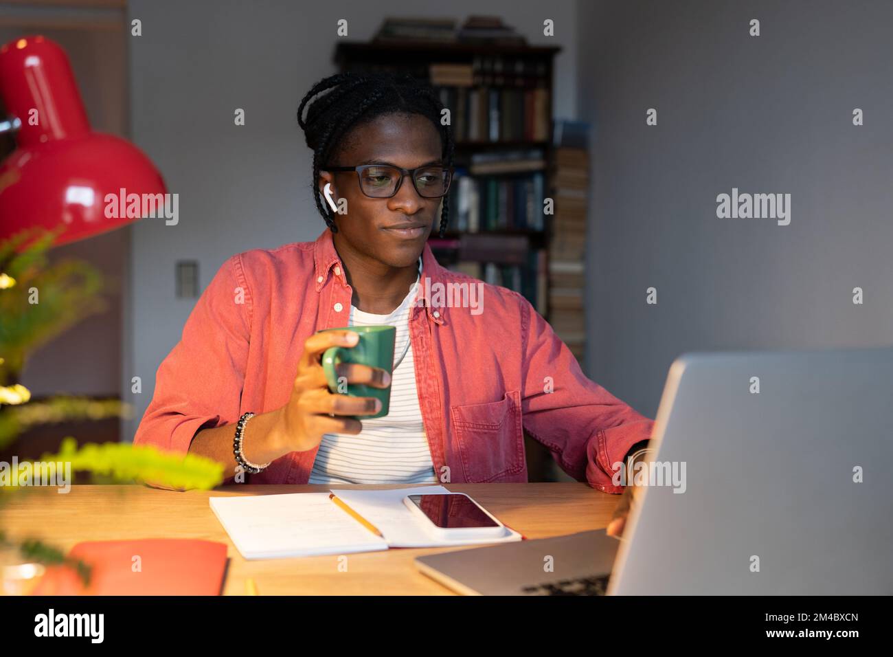 Young African millennial guy student using laptop for remote learning, studying online at home Stock Photo