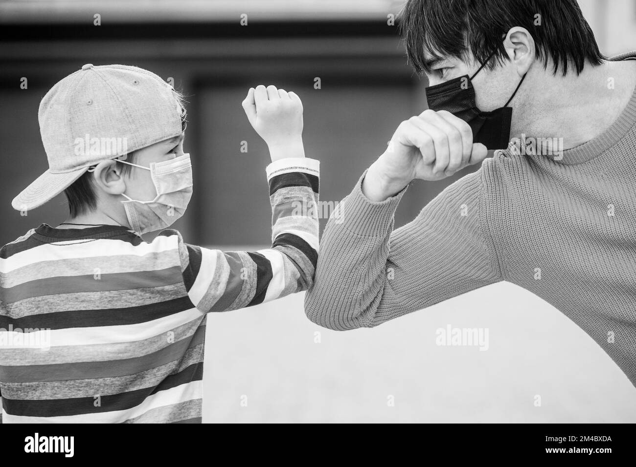 Protective measures. Father puts her son a face protective mask outdoors. Black and white Stock Photo