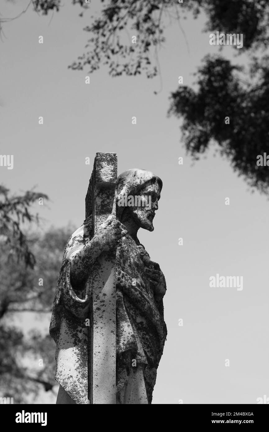 A stone statue of Jesus Christ carrying the cross in a black and white ...