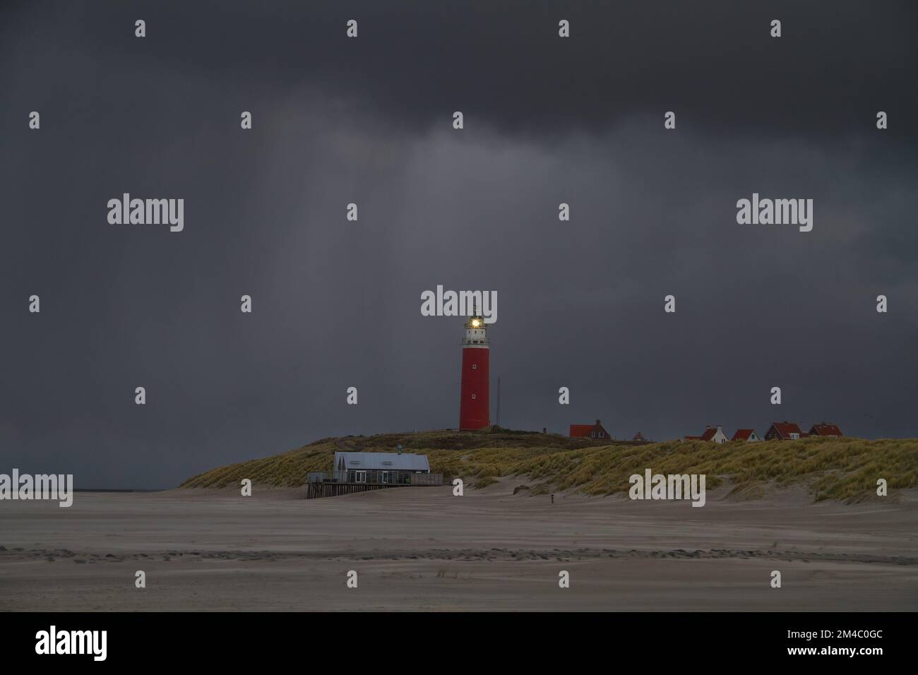 Lighthouse on dunes, rain at nightfall, light in the darkness Stock Photo
