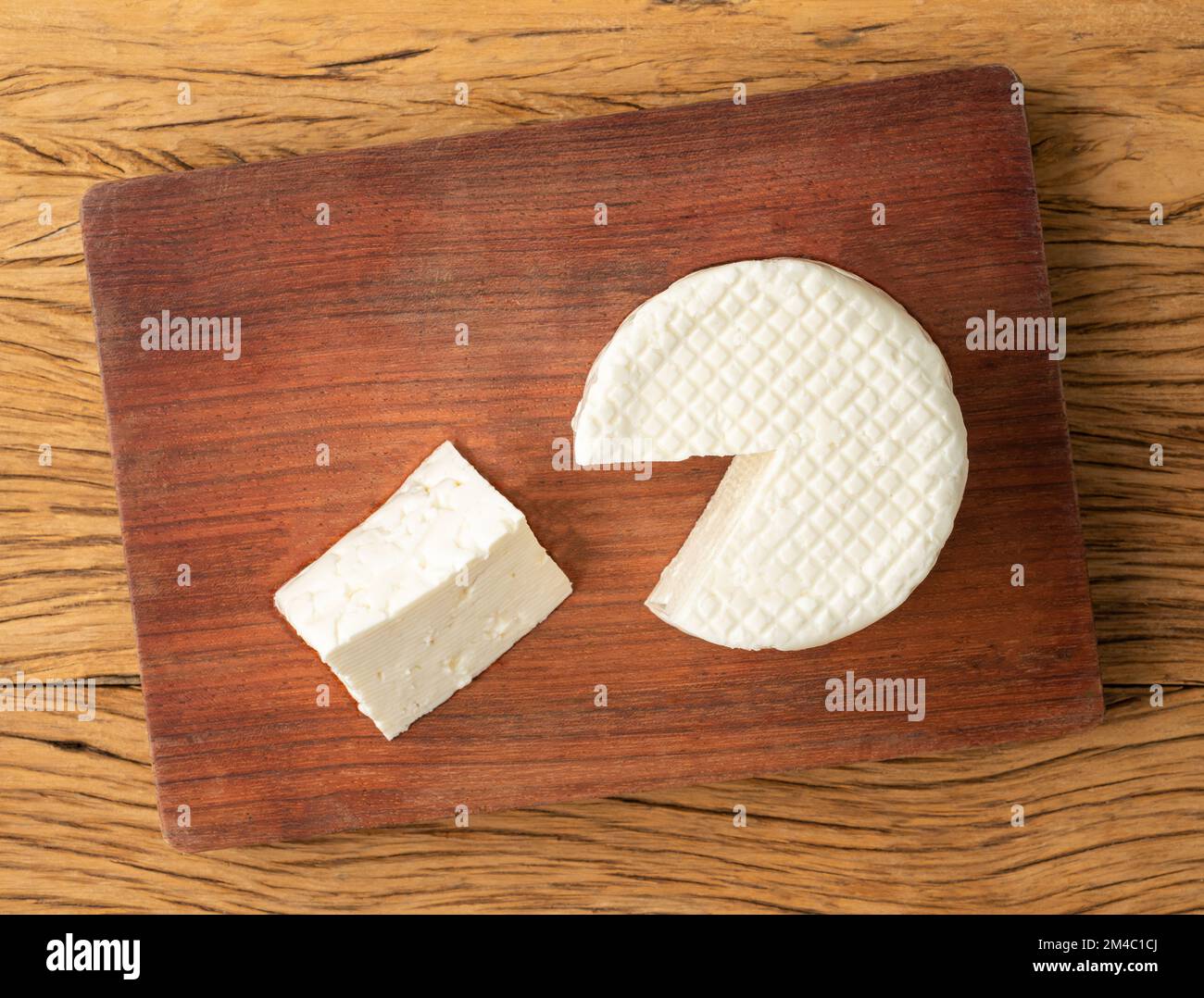 Frescal cheese, typical brazilian fresh white cheese with slice over wooden table. Stock Photo