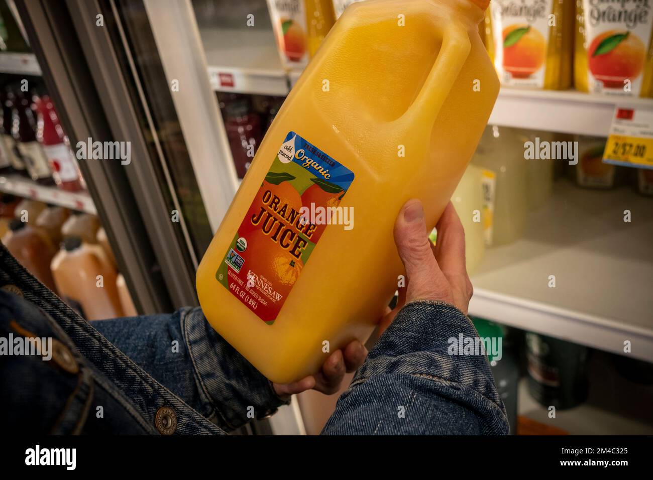 A shopper chooses a bottle of Kennesaw brand organic  Florida orange juice in a supermarket in New York on Wednesday, December 14, 2022. Citrus greening and extreme weather combined are expected to effect FloridaÕs orange crop driving it to the lowest level in over 80 years.  (© Richard B. Levine) Stock Photo