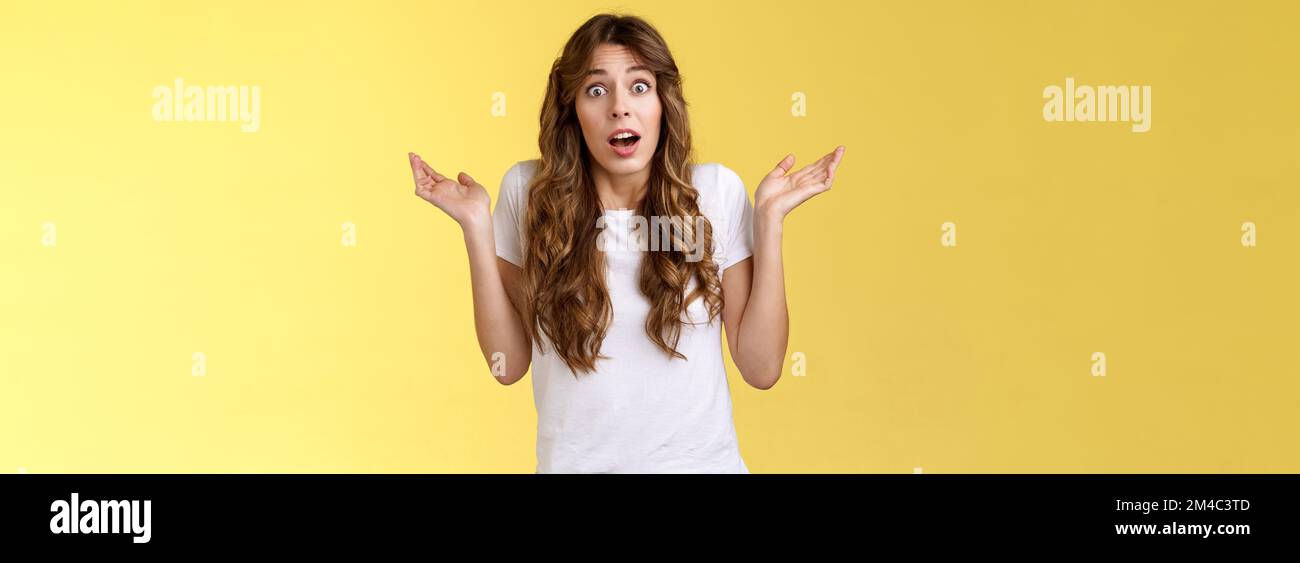I not know. Clueless confused cute nervous young woman shrugging hands raised sideways full disbelief questioned expression lift eyebrows puzzled Stock Photo