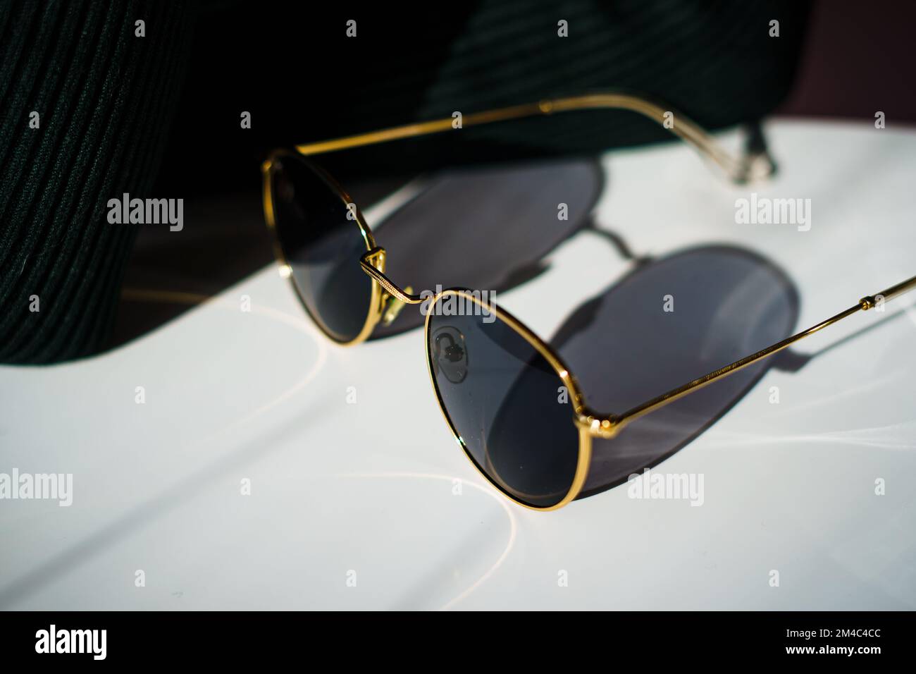 A closeup of Sunglasses with golden rim on a table dropping shadow Stock Photo