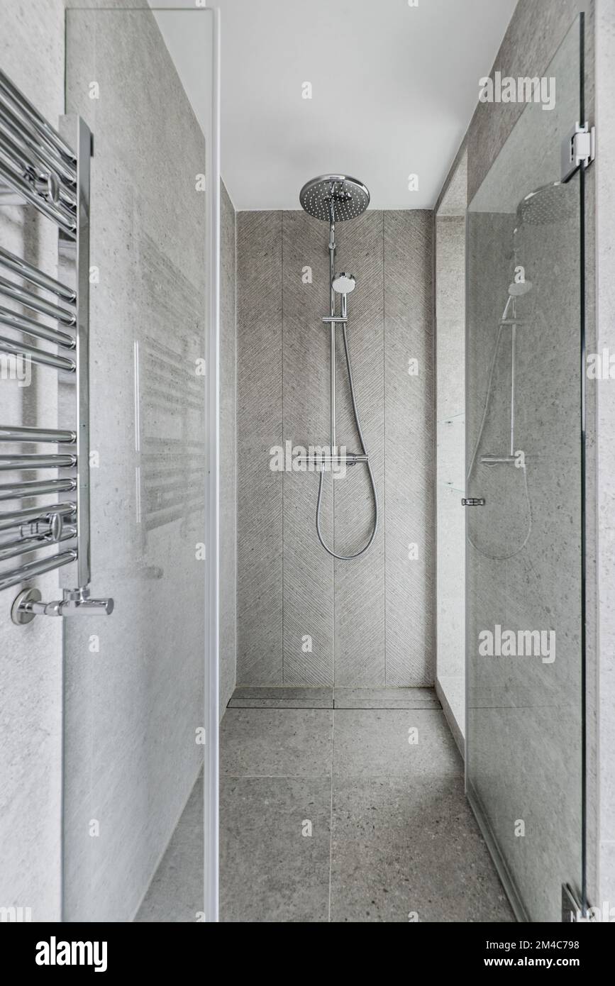 Shower cabin with stone cladding on walls and floors, glass door with