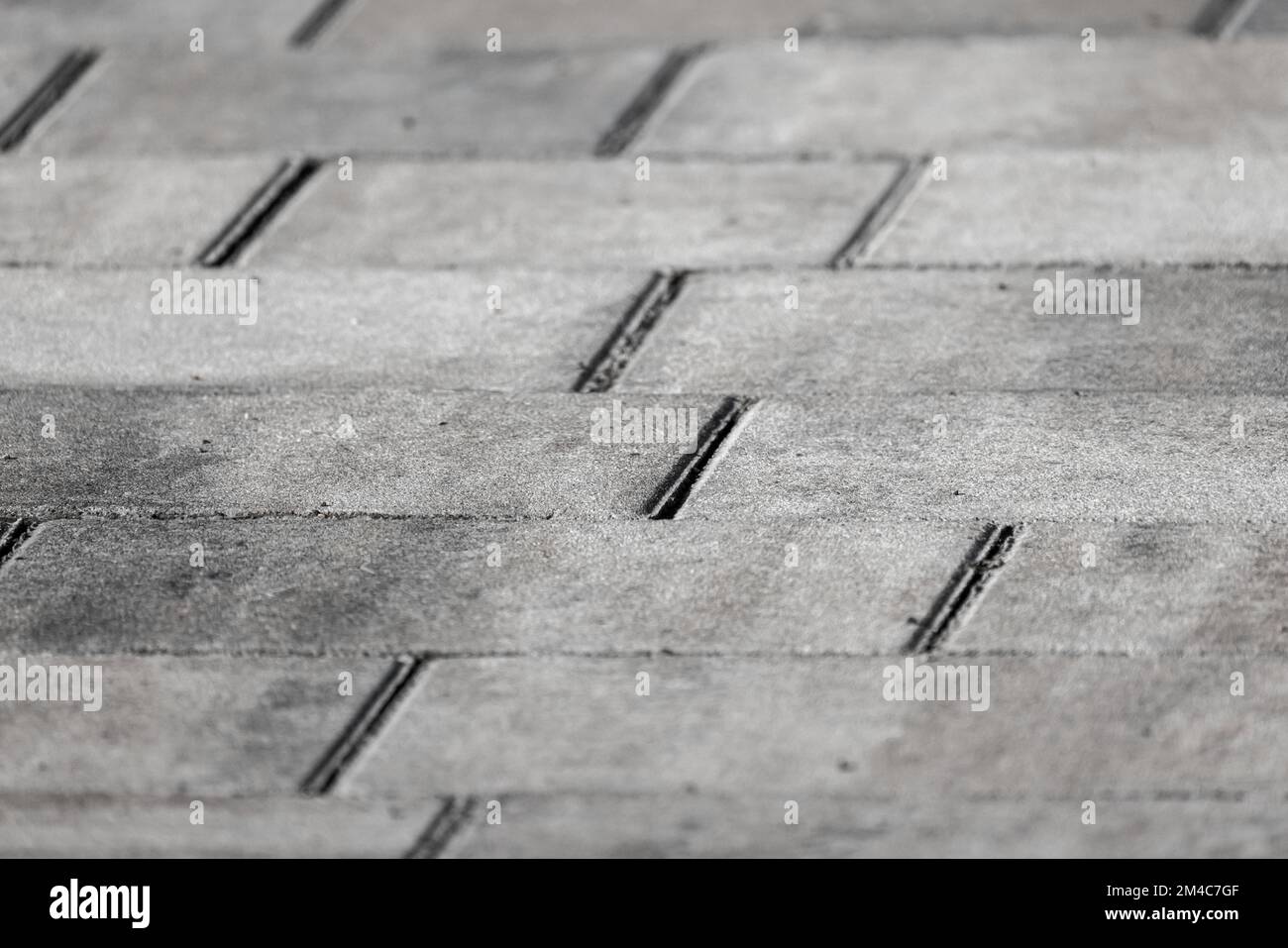 Gray concrete cobble road background, paving slabs close-up photo with selective soft focus Stock Photo