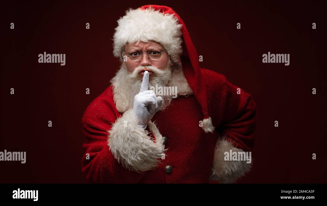 Hush i prepare x-mas gifts. Serious Santa Claus man put finger lips keep voiceless speechless private season newyear news Stock Photo