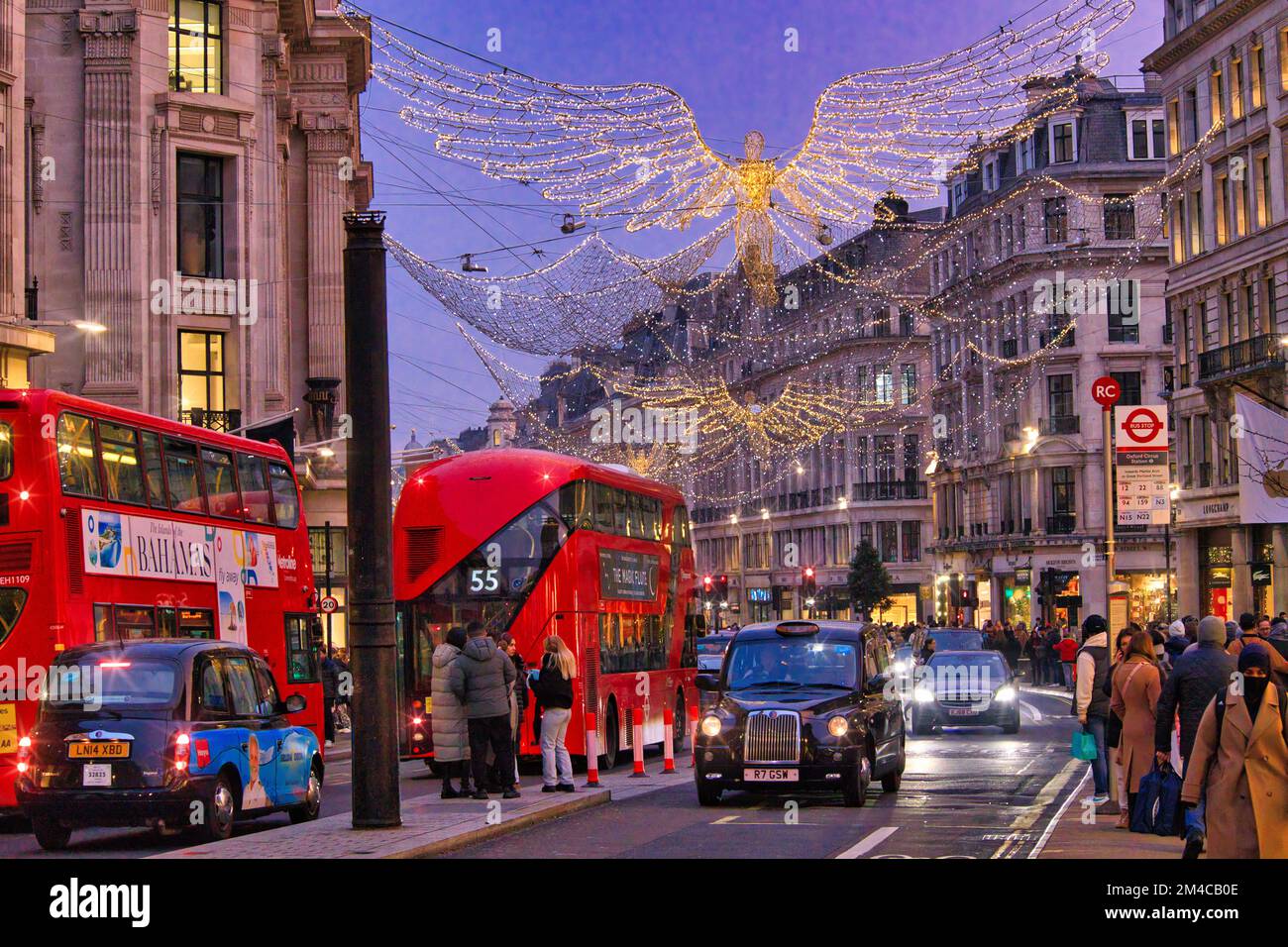 Regent Street, London - Crowds of shoppers walking between brightly lit department stores and holiday traffic underneath Christmas lights Stock Photo