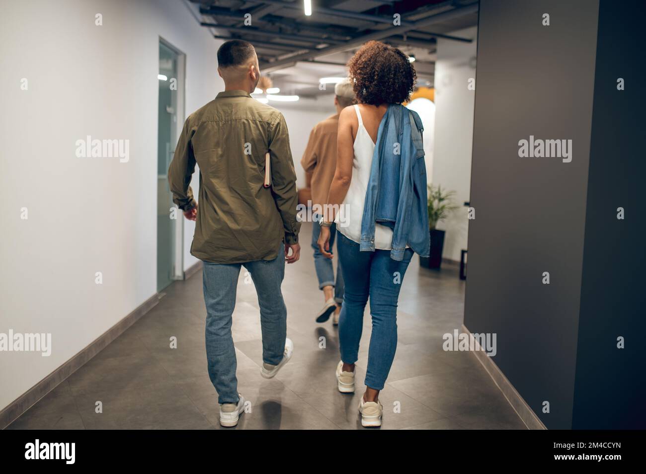 Group of three company employees in a well-lit hallway Stock Photo