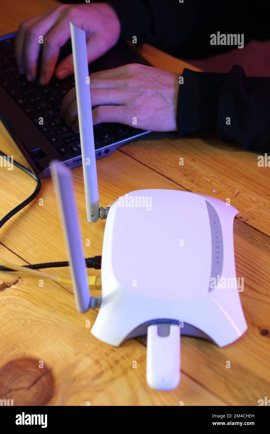 router with inserted gsm modem on table next to laptop and person