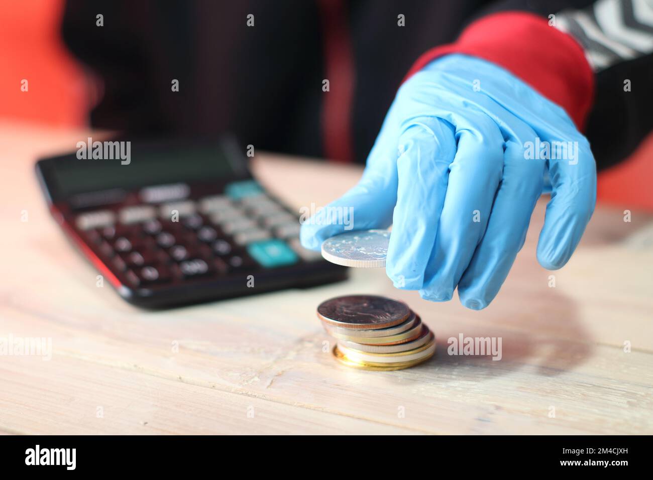 person in blue gloves holding a silver coin over a pile of coins